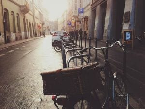 Empty city street with parked cars and a bicycle with a wicker basket.