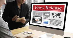 Business meeting discussing press release on computer screen in office setting.